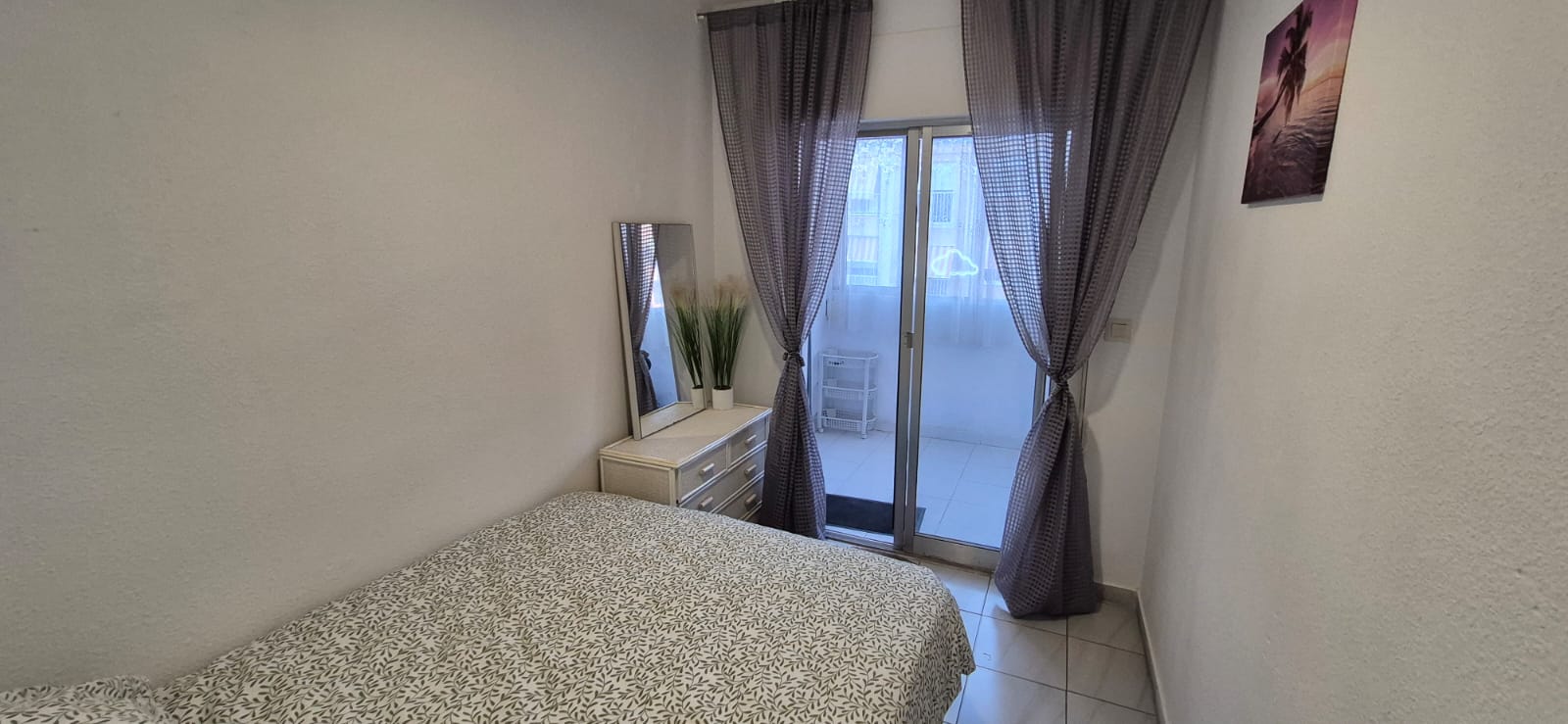 Bedroom with double bed, dresser with mirror and access to the veranda