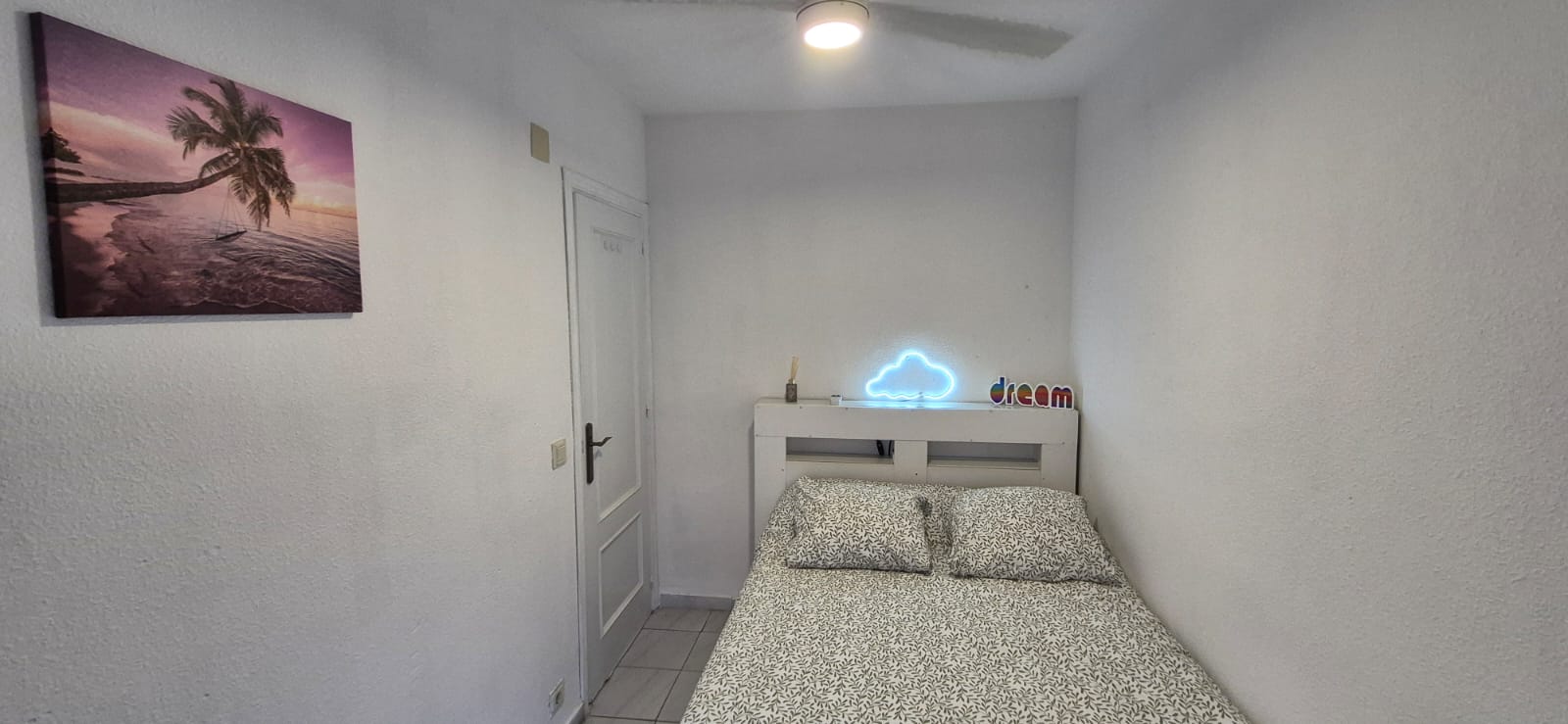 Cosy bedroom with double bed and decorative neon light